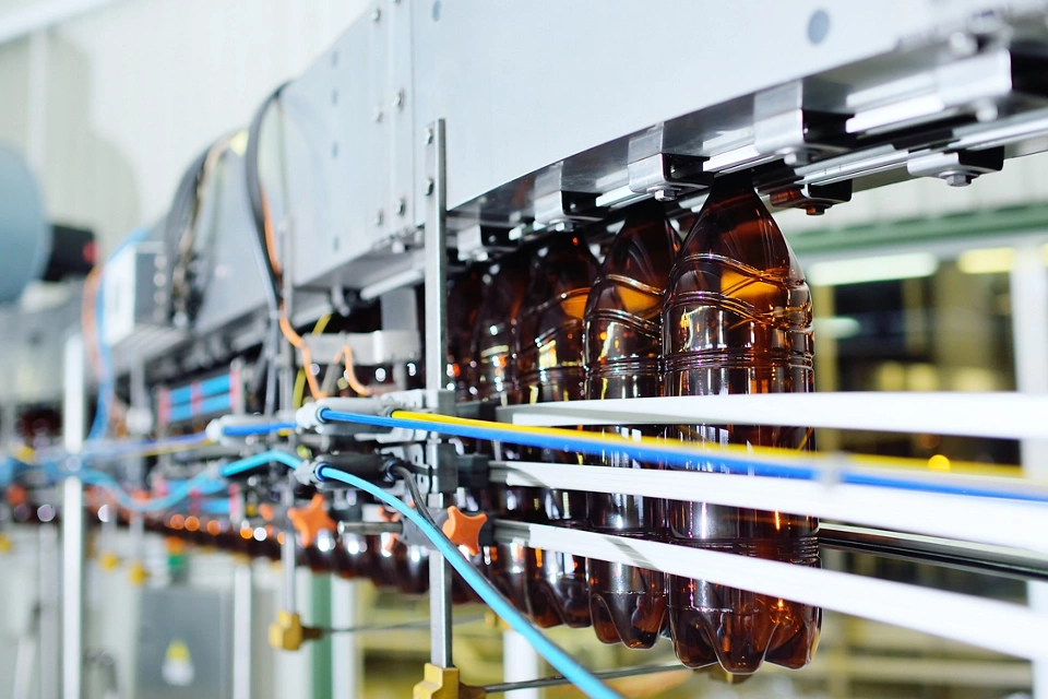 production of large-capacity plastic bottles for beverages, water and sunflower oil. Empty plastic PET bottles of yellow color on a conveyor belt.