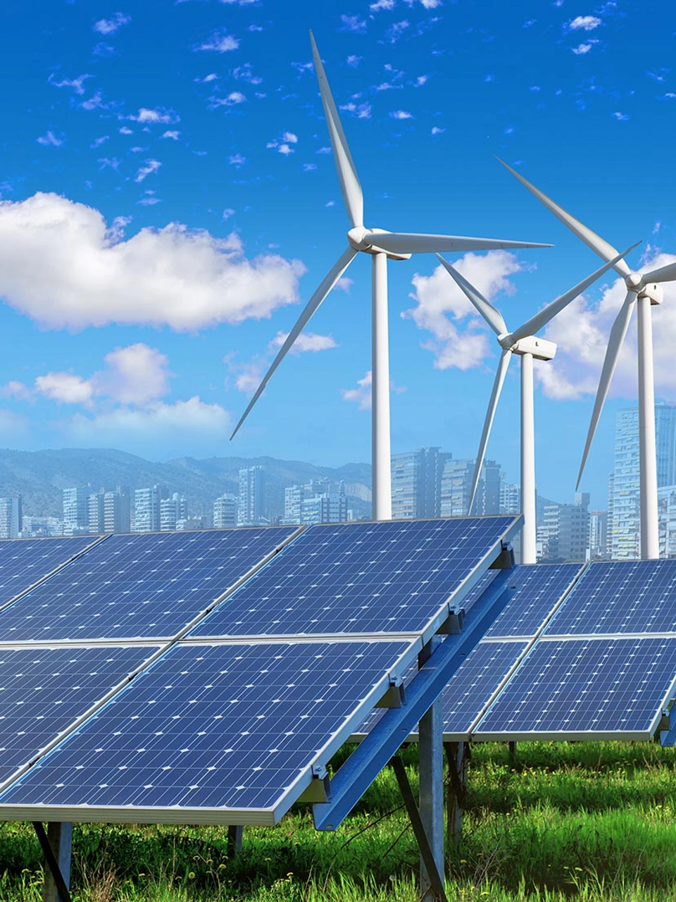 solar panels and wind turbines under blue sky and clouds with city on horizon