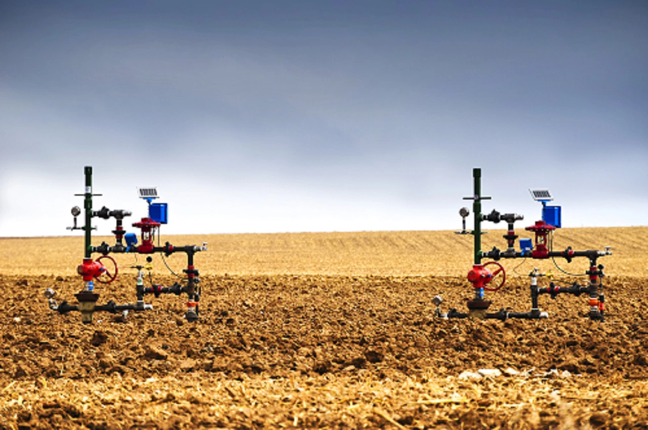 Natural gas wellheads in a plowed cornfield.