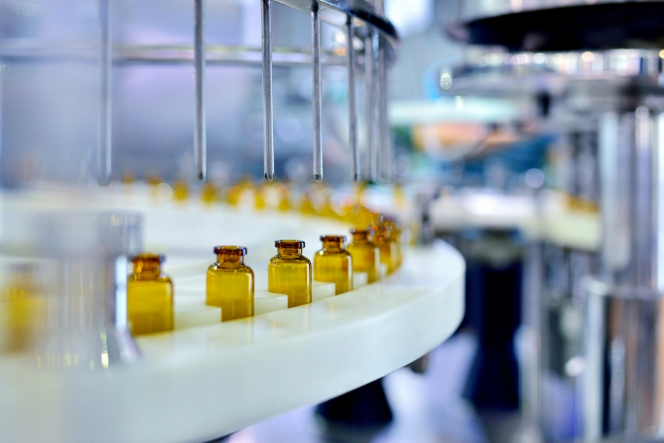 Cloes-up of brown glass bottle filling at production line.