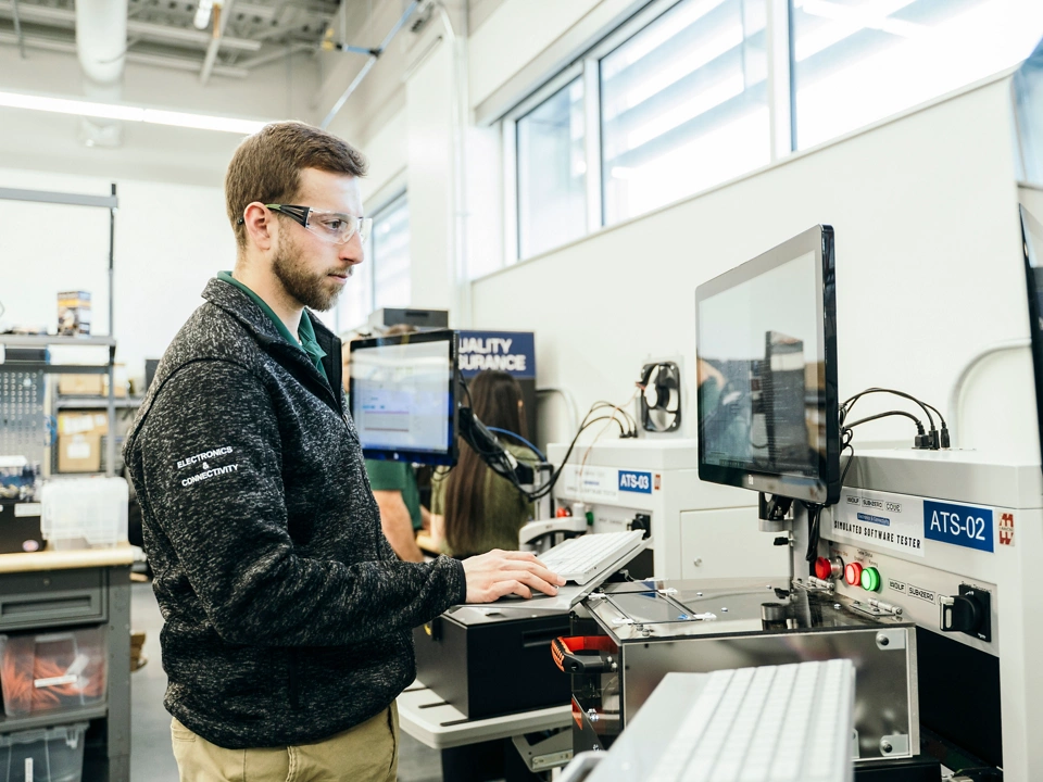 Engineer operating a hardware-in-the-loop (HIL) test system based on NI PXI hardware and NI software to validate embedded control algorithms.