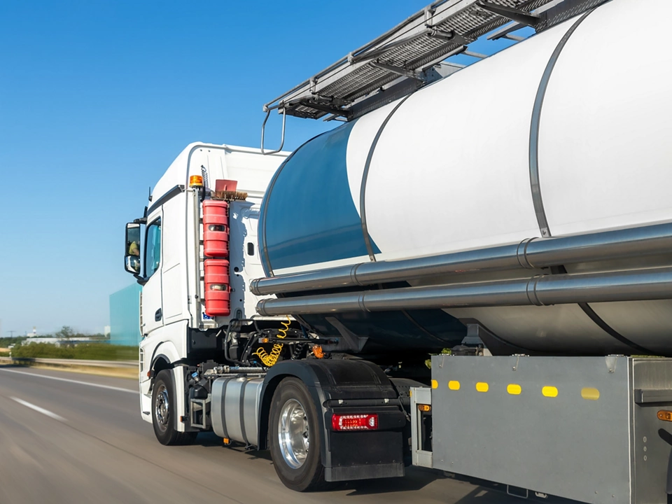 White big modern tanker shipment cargo commercial semi trailer truck moving fast on motorway road city urban suburb. Business distribution logistics service. Lorry driving highway sunny day.