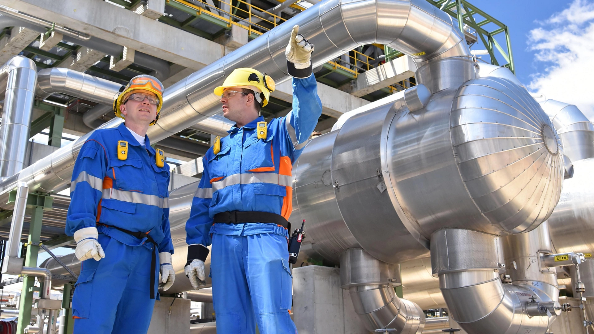 teamwork: group of industrial workers in a refinery - oil processing equipment and machinery